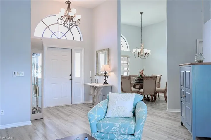 Foyer with a notable chandelier, light hardwood / wood-style flooring, and a towering ceiling