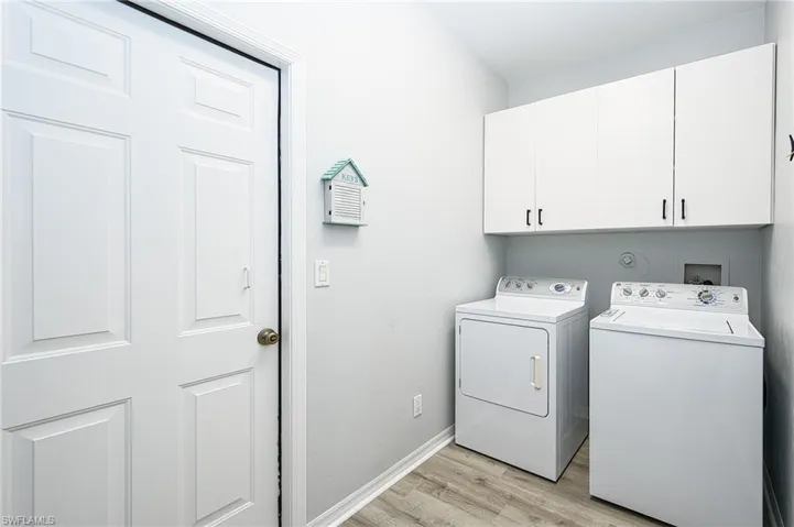 Laundry area featuring washer and dryer, light wood-type flooring, and cabinets