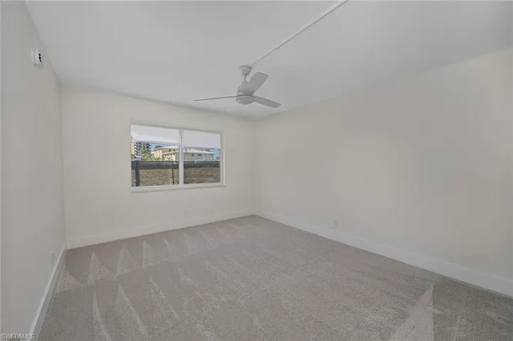 Carpeted empty room featuring a ceiling fan and baseboards