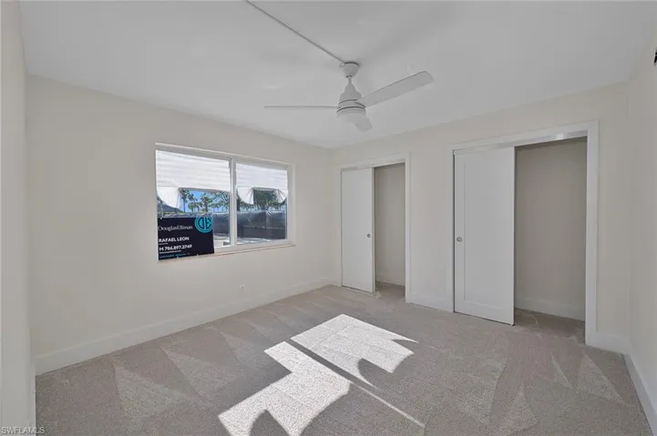 Unfurnished bedroom featuring baseboards, carpet flooring, two closets, and ceiling fan