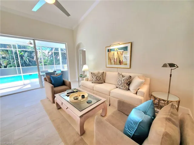 Living room with high vaulted ceiling, tile flooring, ornamental molding, and ceiling fan