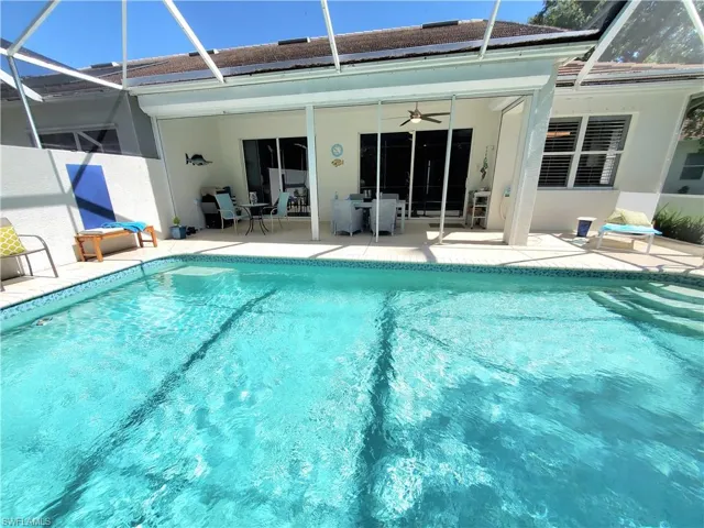 View of swimming pool featuring a patio, glass enclosure, and ceiling fan