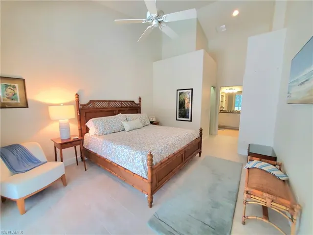 Bedroom with high vaulted ceiling, ensuite bathroom, ceiling fan, and tile floors