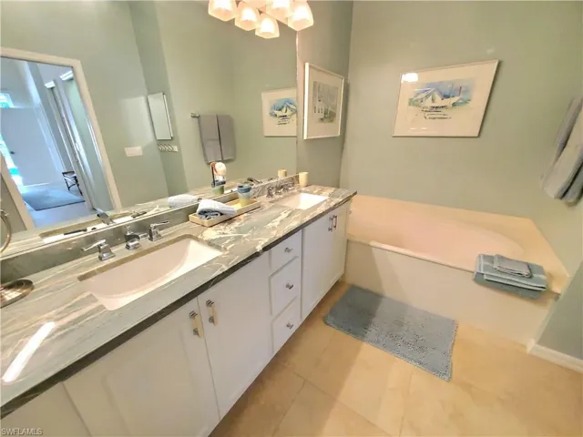 Bathroom featuring tile floors, a washtub, oversized vanity, and dual sinks