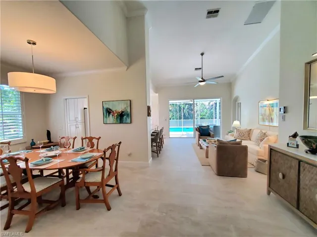 Tiled dining area featuring high vaulted ceiling, ceiling fan, and crown molding
