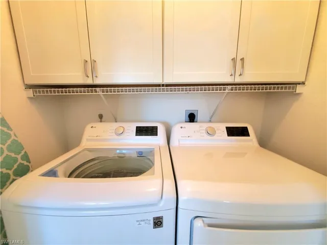 Washroom featuring washer and dryer, electric dryer hookup, and cabinets