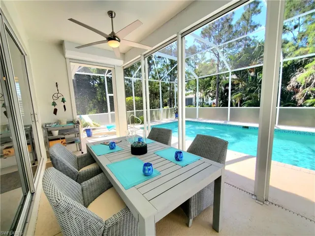 View of pool featuring ceiling fan, glass enclosure, and a patio