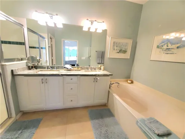 Bathroom featuring shower with separate bathtub, oversized vanity, dual sinks, and tile floors