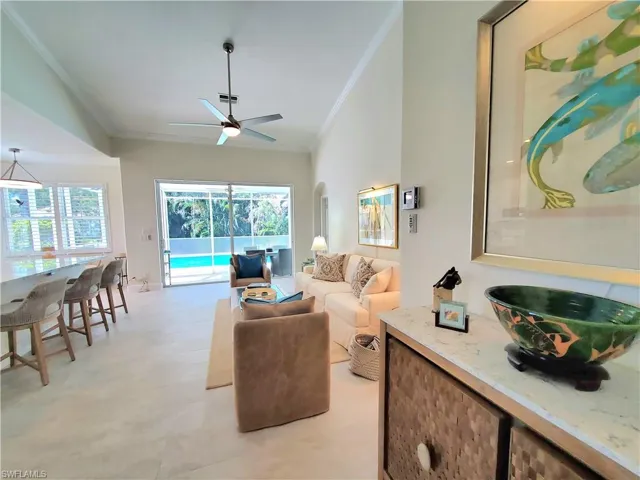 Living room with high vaulted ceiling, ornamental molding, ceiling fan, and light tile floors