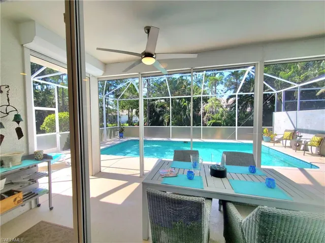View of pool with a patio, glass enclosure, and ceiling fan