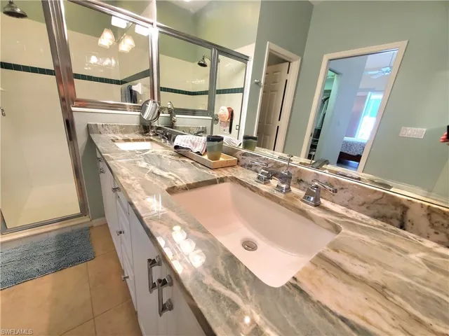 Bathroom featuring tile floors, a shower with shower door, ceiling fan, and double sink vanity