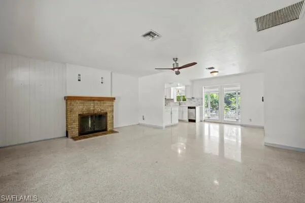 Unfurnished living room with ceiling fan and a brick fireplace