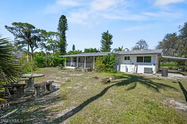 Back of property with central AC unit and a lawn