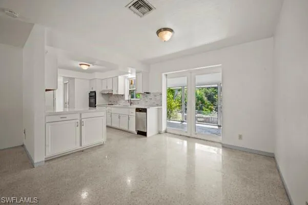 Kitchen with white cabinets, stainless steel dishwasher, backsplash, sink, and oven
