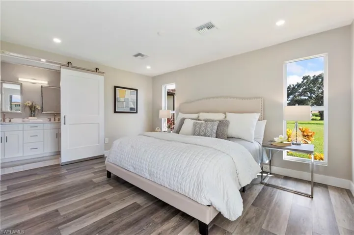 Bedroom featuring a barn door, connected bathroom, and hardwood / wood-style floors