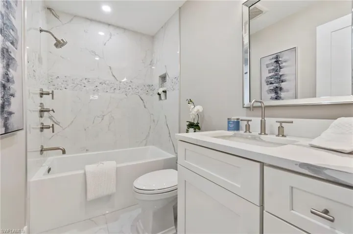 Full bathroom with tiled shower / bath combo, vanity, and toilet
