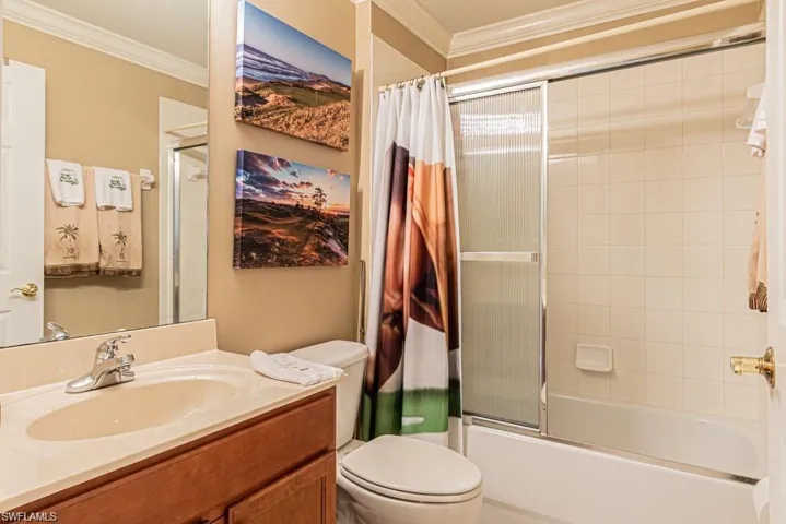 Full bathroom with shower / bathtub combination with curtain, crown molding, vanity, and toilet