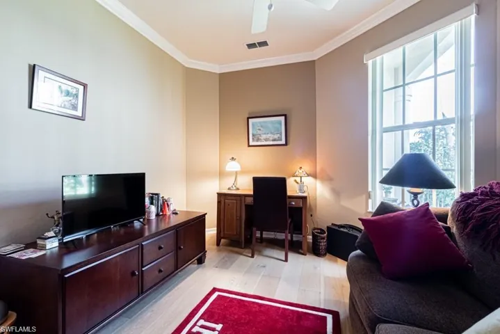 Living room with ceiling fan, a healthy amount of sunlight, ornamental molding, and light hardwood / wood-style flooring