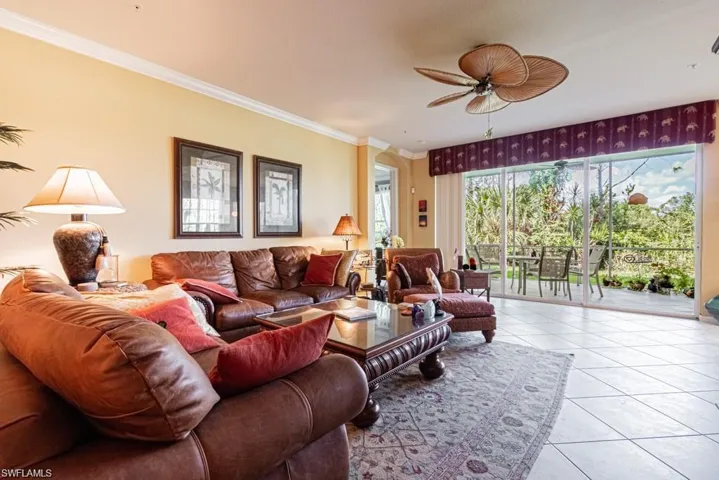 Living room featuring ceiling fan, light tile patterned floors, and crown molding