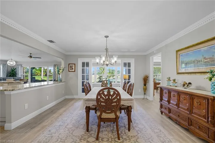 Dining area featuring wood-finish flooring, crown molding, and a chandelier