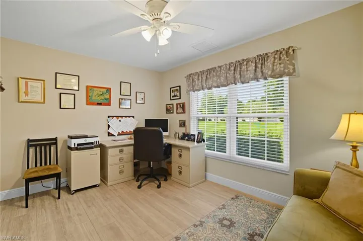 Inviting room featuring a large window with horizontal blinds, light wood-finish flooring, and a ceiling fan with integrated lighting