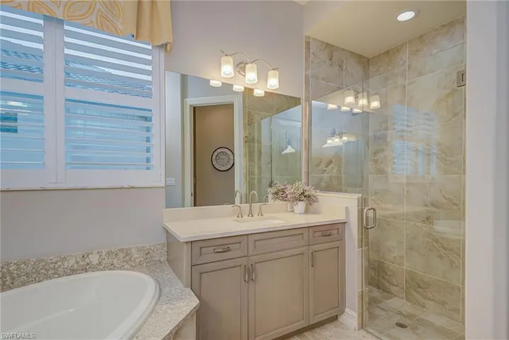 Bathroom featuring a stall shower, a bath, and vanity