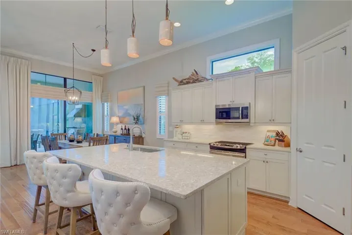 Kitchen featuring appliances with stainless steel finishes, healthy amount of natural light, tasteful backsplash, crown molding, and white cabinets