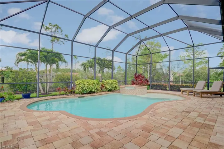 View of swimming pool with a patio, glass enclosure, and a pool with connected hot tub