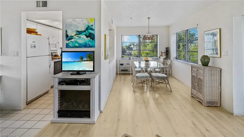 Dining area with walls of windows, electric fireplace, and kitchen view.