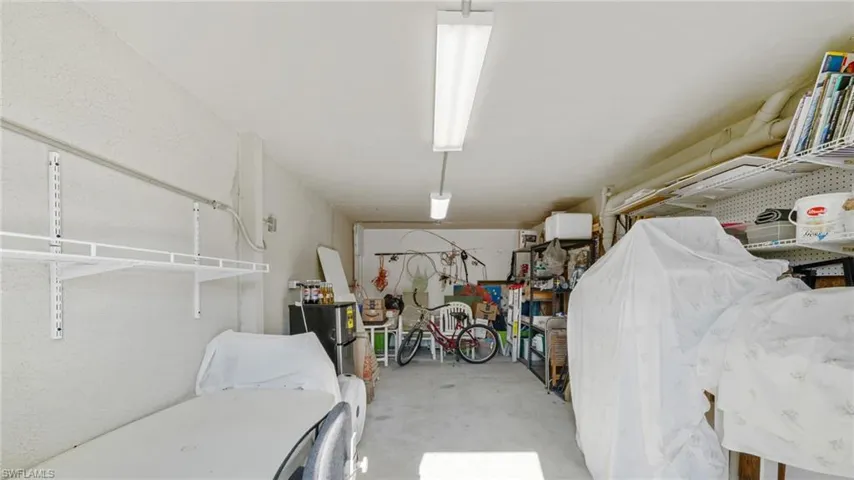 Ground floor Storage or workroom with pegboards, shelving, and a mini-fridge