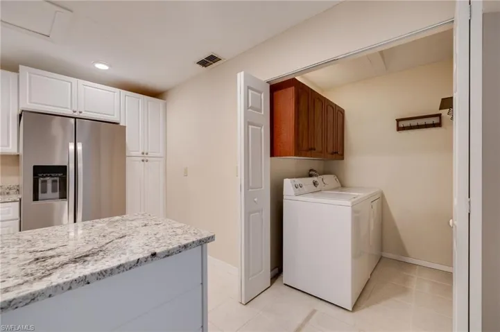 Laundry room featuring light tile patterned floors, separate washer and dryer, cabinet space, and recessed lighting