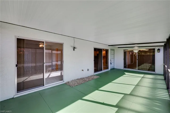 Unfurnished sunroom featuring a ceiling fan and a patio area