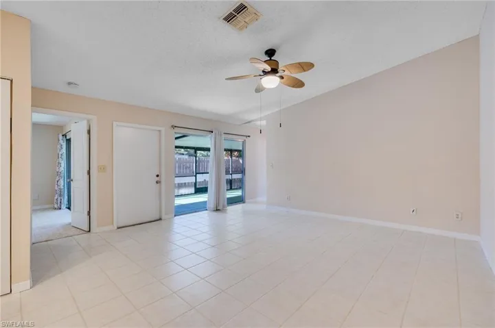 Empty room featuring a textured ceiling, a ceiling fan, lofted ceiling, and light tile patterned floors