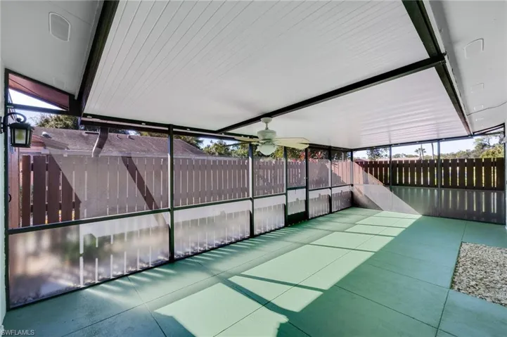 Fenced backyard with ceiling fan and a sunroom