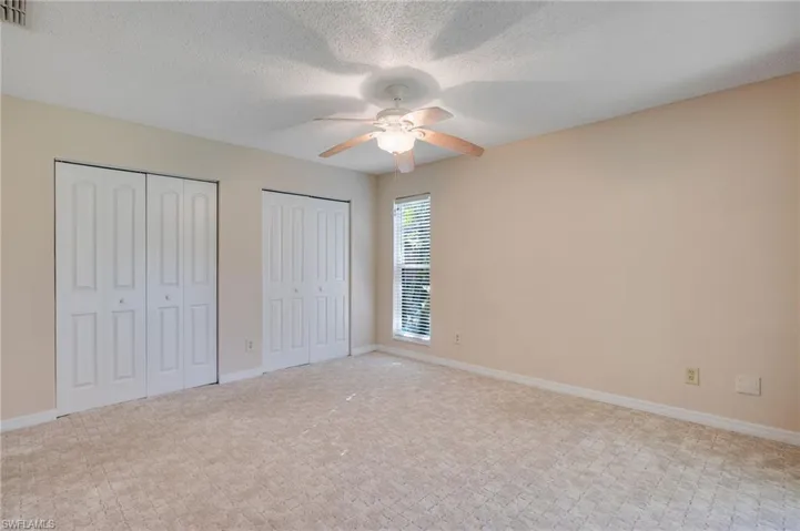 Unfurnished bedroom featuring multiple closets, a textured ceiling, and ceiling fan