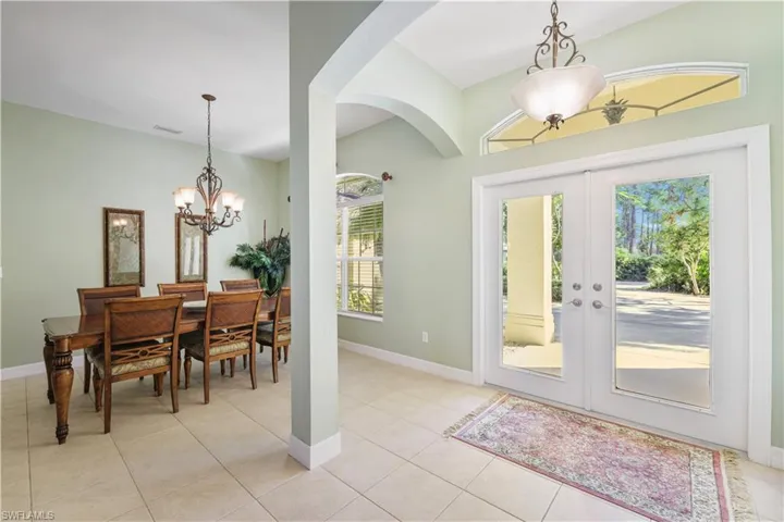 Entrance foyer featuring a chandelier, light tile patterned floors, french doors, and arched walkways