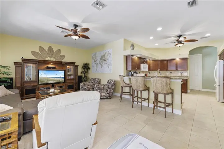Living room featuring ceiling fan, light tile patterned floors, arched walkways, and recessed lighting
