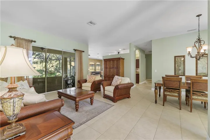 Living room with light tile patterned floors, arched walkways, and a chandelier