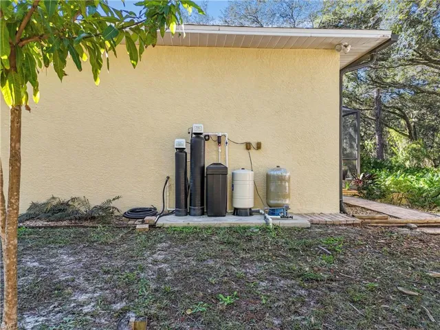Exterior view of stucco siding, a water softener system, and a water pressure tank