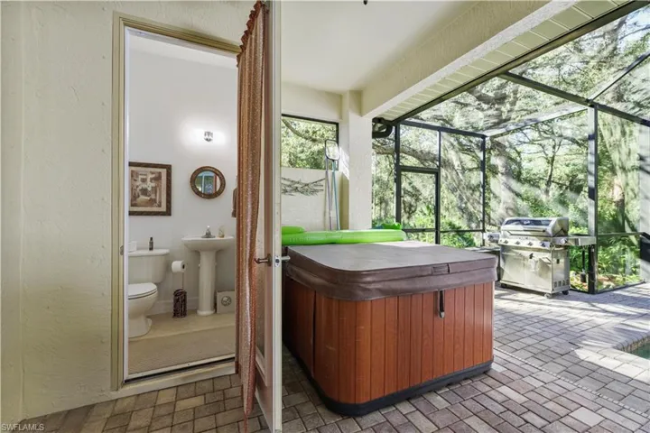 Sunroom / solarium featuring a hot tub and a sink