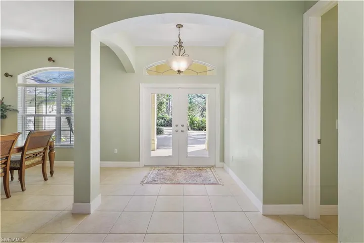 Entryway with french doors, light tile patterned floors, plenty of natural light, and arched walkways