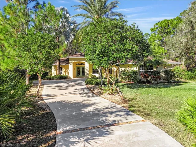 View of front of property with french doors, driveway, stucco siding, and a front lawn