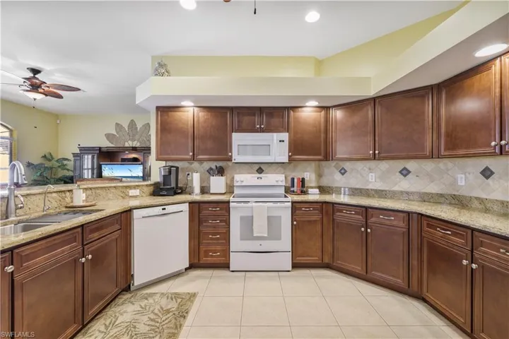 Kitchen featuring ceiling fan, white appliances, light stone countertops, light tile patterned flooring, and recessed lighting