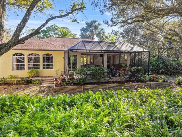 Back of property featuring a sunroom, stucco siding, glass enclosure, and roof with shingles