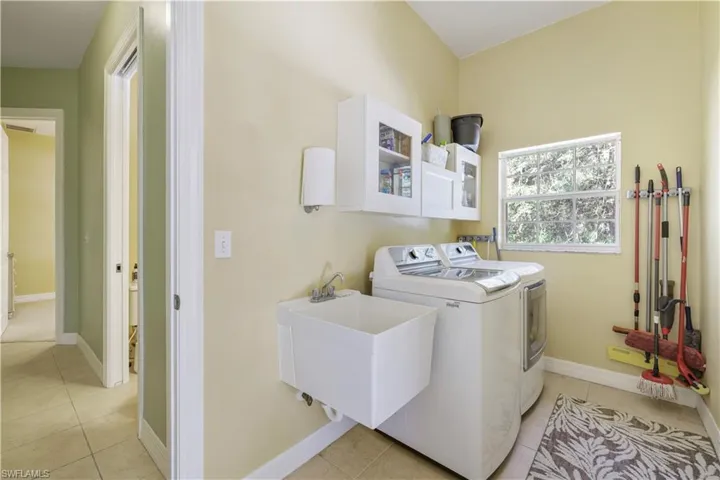 Laundry area with independent washer and dryer and light tile patterned floors