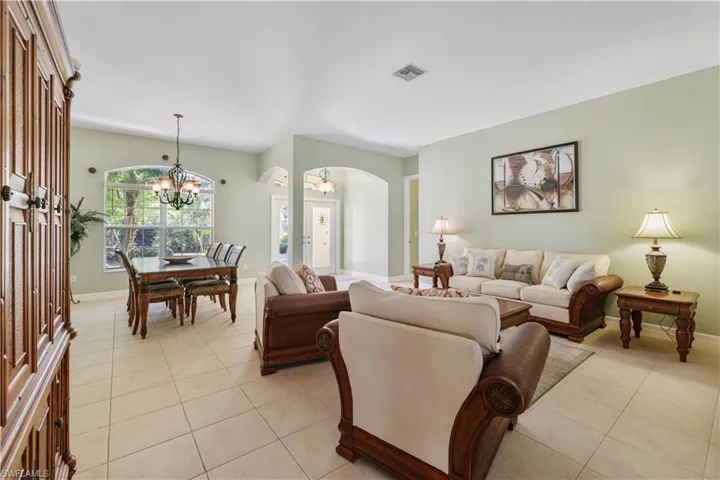 Living room featuring light tile patterned flooring, arched walkways, and a chandelier