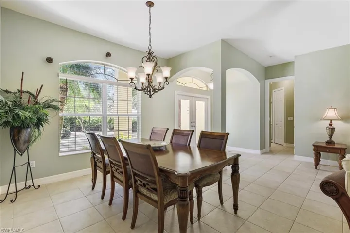 Dining space featuring french doors, light tile patterned flooring, a chandelier, and arched walkways