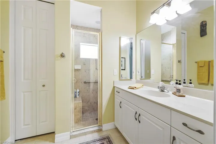 Bathroom featuring a closet, vanity, a shower stall, and light tile patterned floors