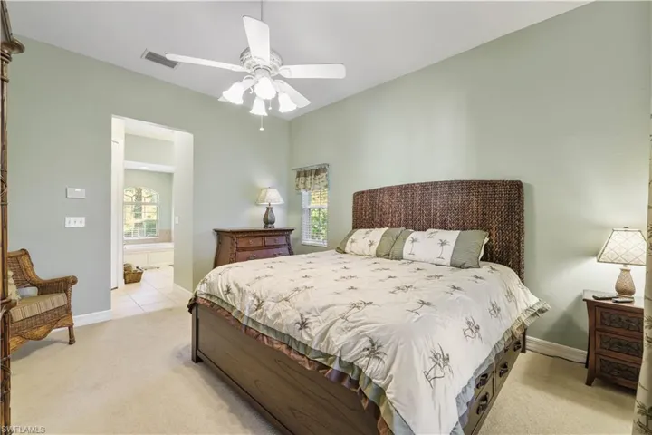 Bedroom with light carpet, multiple windows, and ceiling fan
