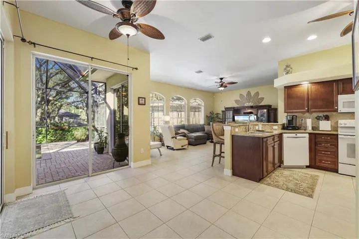 Kitchen featuring open floor plan, a peninsula, light stone countertops, ceiling fan, and decorative backsplash